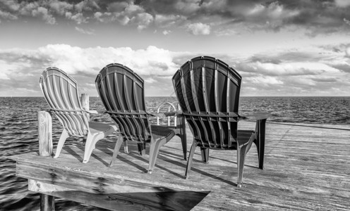 木制码头上椅子的黑白视图图片