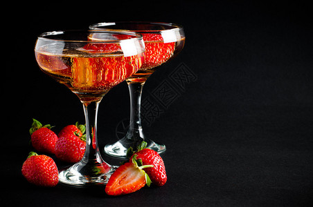 两杯冷香槟黑底带草莓的两杯图片