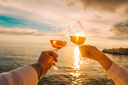 一对夫妇在海边的日落和喝着葡萄酒休图片