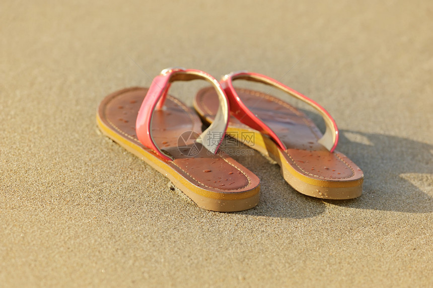 暑假概念沙滩上的凉鞋图片