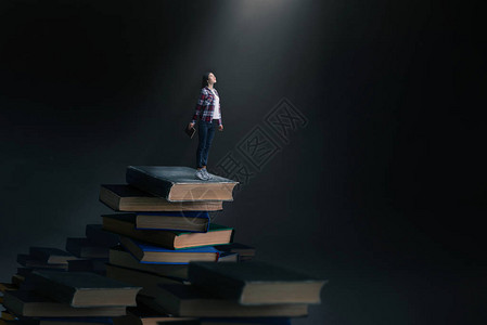 小年轻女子站在大书和教科书的山上图片
