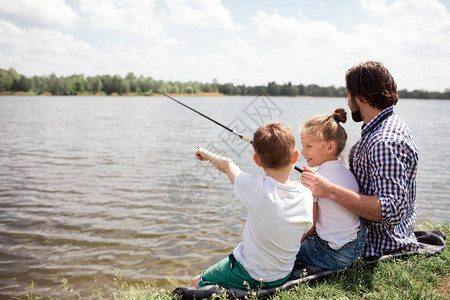 一张男人和他的孩子们一起坐在河岸上的照片图片