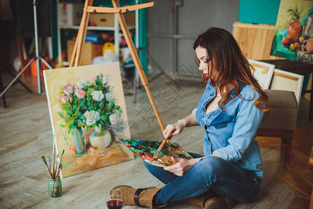 女艺术家在工作室里画一幅画创造沉思画家女孩在车间用油画颜料在画布上画出一幅五图片