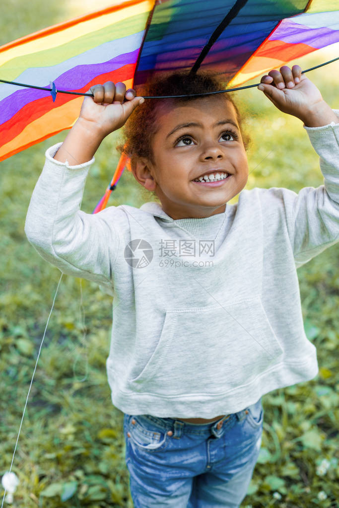 带着彩虹风筝在公园头顶上举着彩虹风图片