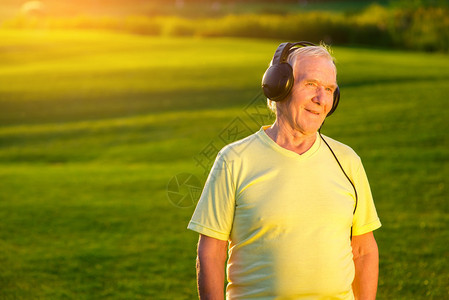 戴耳机的老人绿色草地背景上的人我最喜欢的广播电背景图片
