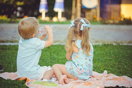 两个孩子在公园草地上男孩在喝水望向远方图片