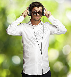 年轻人在自然背景下使用耳机听音乐的肖像画图片