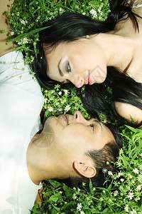 年轻夫妇面对躺在草地上图片