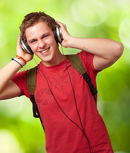 年轻学生在自然背景上用耳机聆听音乐的欢图片