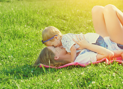 母亲和女儿躺在绿色的草地上玩耍图片