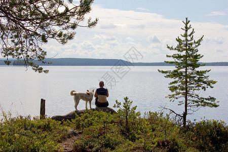 湖边的岩石上坐着一条狗的女孩图片