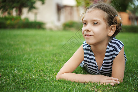 小可爱的笑脸女孩躺在绿草地上夏图片