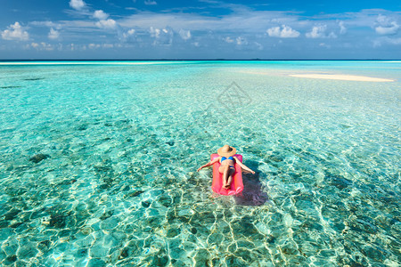 女人在沙滩水上的充气床垫上放松图片