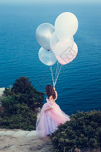 穿粉红裙子的年轻时尚美女拿着气球对图片