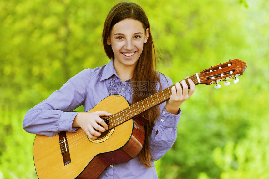 穿着蓝衬衫的美丽笑脸少女弹吉他图片