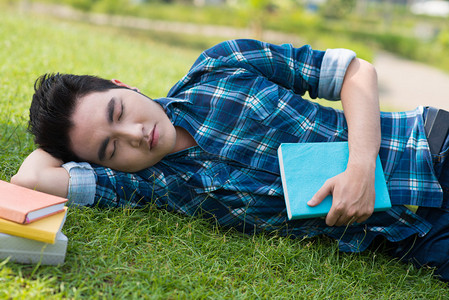 近距离拍摄一个睡不着的学生厌倦在草地图片