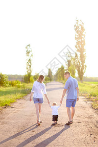 年轻的父母带着小婴儿走在路上的背影图片