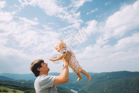 父亲抱着可爱的女婴靠在风景如画的青山上图片