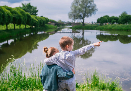 年轻的男孩和女孩看着湖后视图图片