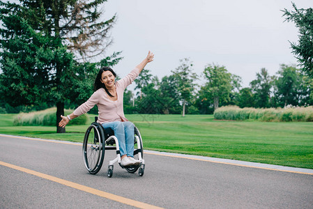 快乐的残疾妇女坐在公园轮椅上时图片