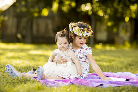 小女孩和婴儿坐在草地上图片