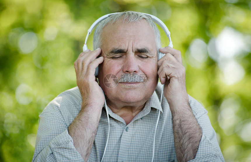 养老金领取者坐在花园里一边听着耳机上的曲子图片