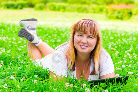幸福的女子躺在绿草地上手里图片
