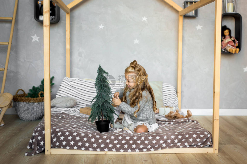 小女孩坐在床上装饰小圣诞树圣诞快图片