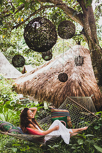 穿着白色衣服的女人在Bali花园吊床上放松图片