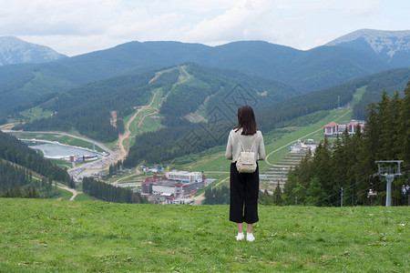 女孩背着包站在山丘上欣赏山峰图片