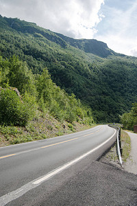 绿色植被覆盖的空沥青路和美丽的山岳图片