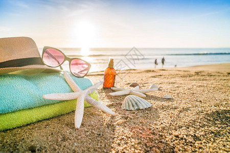 葡萄牙沙滩上的太阳墨镜毛巾帽子防晒霜贝壳和海图片