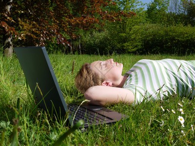 年轻女人躺在草地上梦幻般的眼神笔记本图片