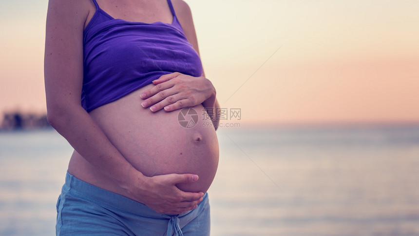 孕妇在海滩上用手拉着肚子图片