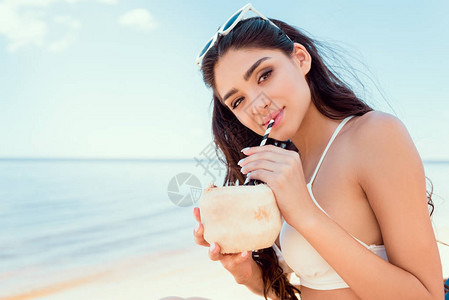 比基尼美女在海滩上喝椰子鸡尾酒图片