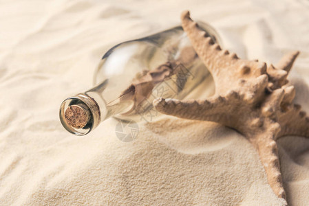 沙滩上带字母和海星的瓶子背景图片