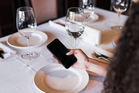 坐在餐厅桌旁使用智能手机的裁图片