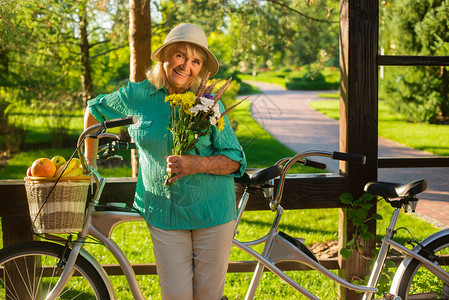 骑自行车时微笑的女人带花的高级女士丈夫送的鲜花周图片