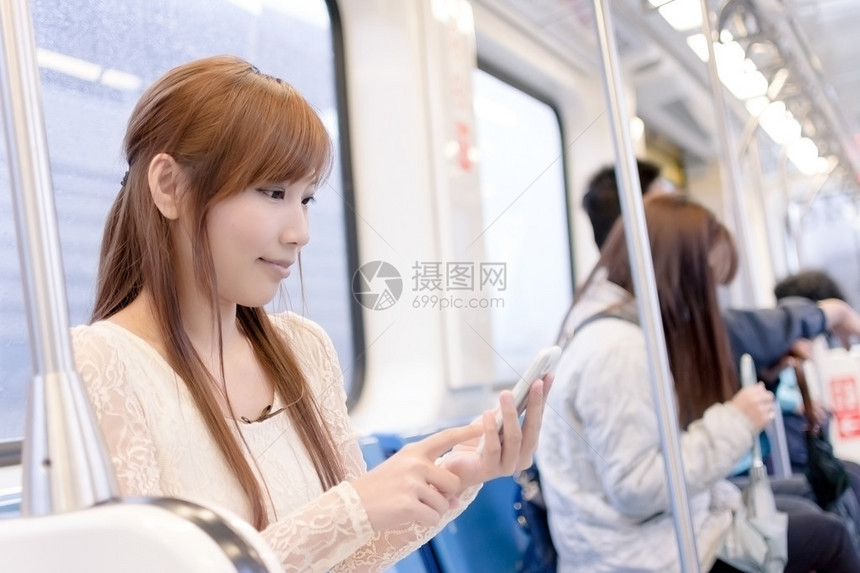 在MRT马车中的亚洲美人使用她的手机图片