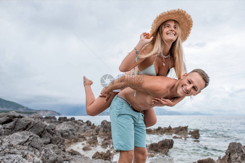 快乐的年轻夫妇搭载在蒙泰内格罗岩石海滩图片