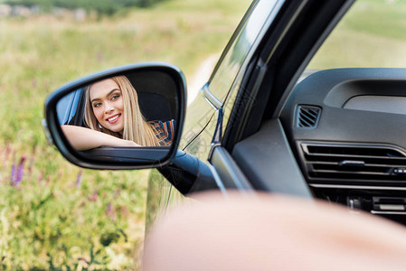 坐在车里看着侧镜的年轻女士笑着看图片