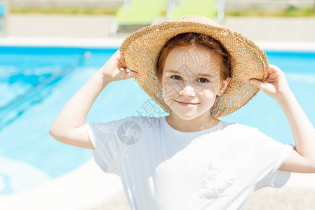 穿着草帽的可爱小孩在游泳池前图片