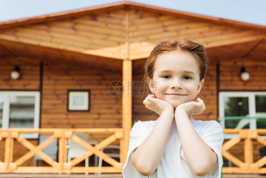 可爱的小孩在木屋前看镜头图片