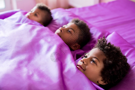 三个黑人男孩在床上紫色床上的黑人男孩是时候去了图片