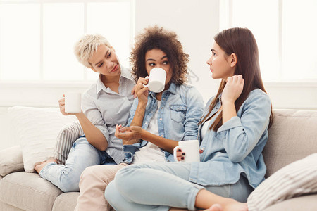 闲话半盏茶三个端着咖啡杯的年轻女人在沙发上聊天背景