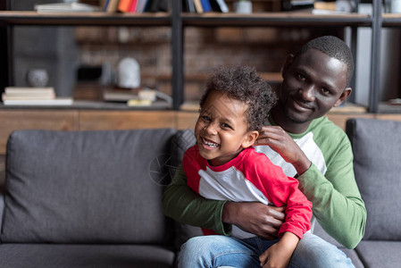 快乐的非洲美国父亲和儿子在家里共图片