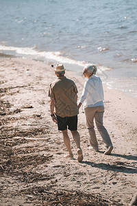 老年夫妇手牵走在沙滩上的背影图片