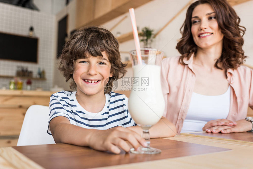 快乐的男孩与一杯奶昔和他微笑的母亲图片