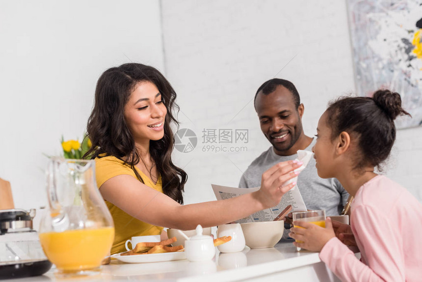 快乐的母亲在早餐后擦拭小女儿的脸而父图片