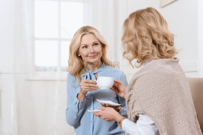 两个中年妇女坐在沙发上喝茶图片